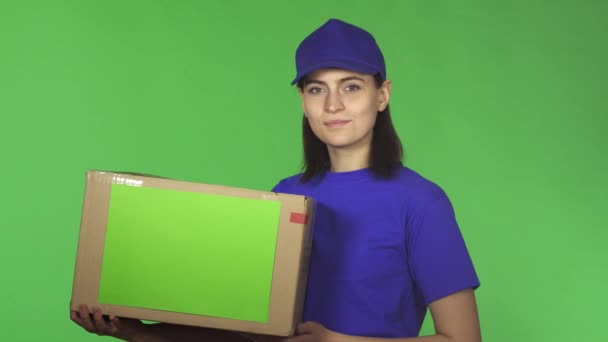 Ελκυστική νεαρή παράδοσης γυναίκα δείχνει μπράβο κρατώντας κουτί από χαρτόνι - Πλάνα, βίντεο