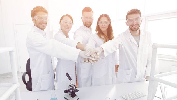 successful team of young scientists with hands clasped together. - Foto, imagen