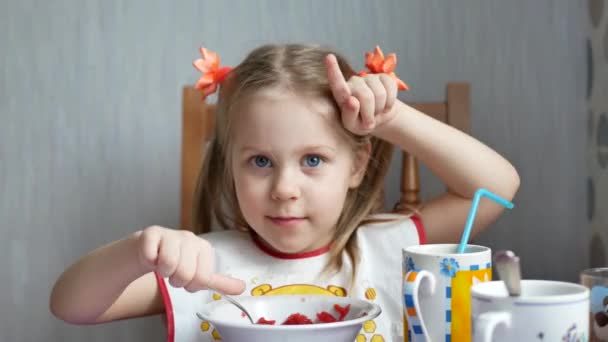 Mała dziewczynka pokazuje jej palce jak rogi krów na kuchnię - Materiał filmowy, wideo