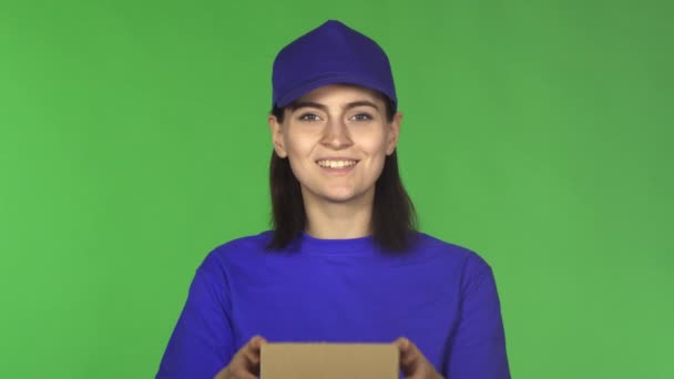 Onnellinen toimitus nainen hymyilee ojentaen pienen paketin kameralle
 - Materiaali, video