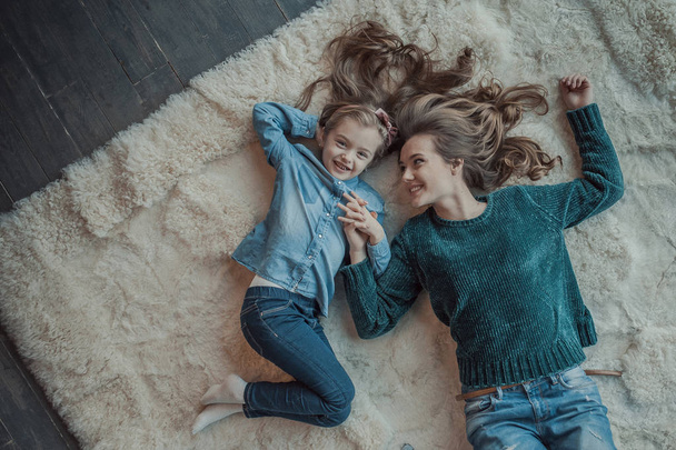 Sonriente madre con su hija en la habitación de la alfombra
 - Foto, imagen