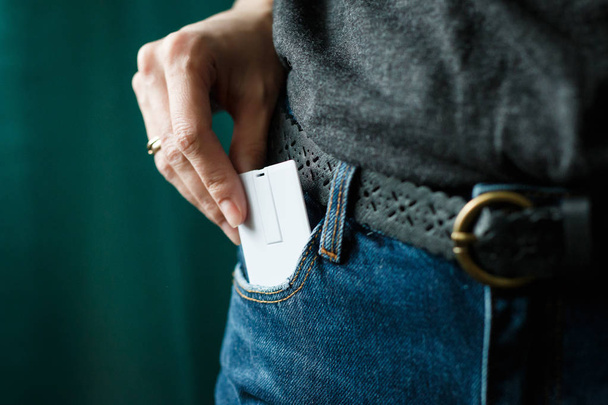 Крупным планом женщина схватила белую карточку в кармане джинсов
  - Фото, изображение