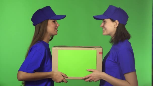 Two cheerful female delivery service workers smiling holding cardboard box - Footage, Video