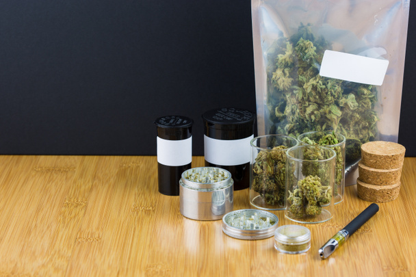 різноманітна марихуана в контейнерах і пластикових пакетах з металобрухтом на дерев'яному столі на чорному фоні
 - Фото, зображення