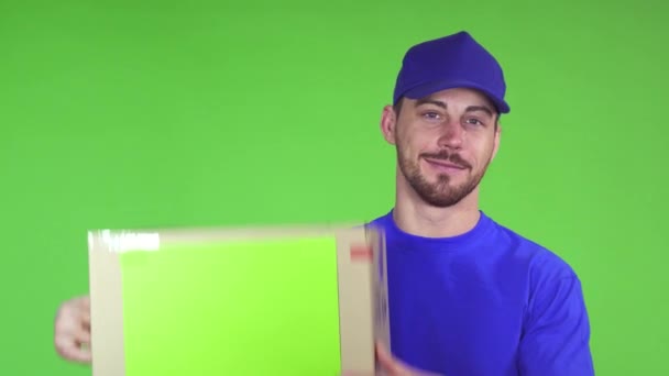 Happy deliveryman smiling putting cardboard box with copyspace on his shoulder - Footage, Video