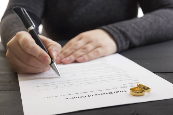 Ręce żony, mąż podpisujący dekret o rozwodzie, rozwiązaniu, unieważnieniu małżeństwa, dokumenty separacyjne, złożeniu papierów rozwodowych lub przedmałżeńskiej umowy przygotowanej przez adwokata. Pierścionek ślubny - Zdjęcie, obraz