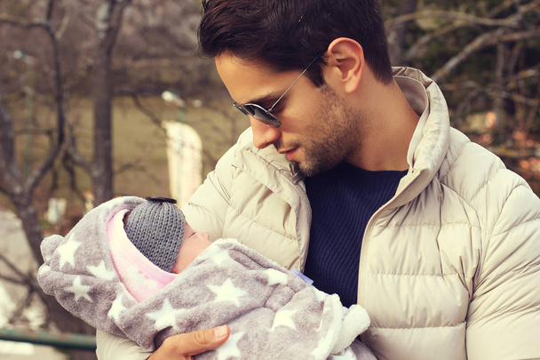Handsome man holding his beautiful baby outdoor  - Photo, Image