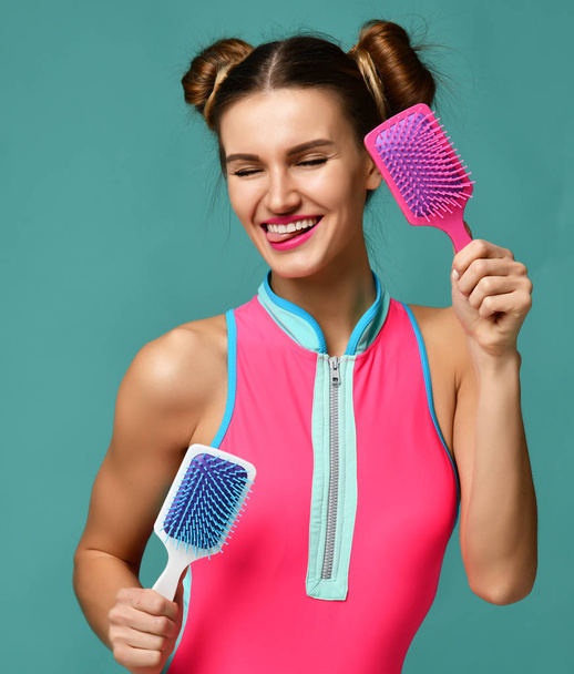 Closeup portrait of happy smiling fashion brunette woman with colorful pink and white big square hair comb brushes  - Zdjęcie, obraz