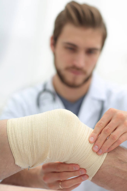 traumatologist examining the bandage on his knee. - Fotografie, Obrázek