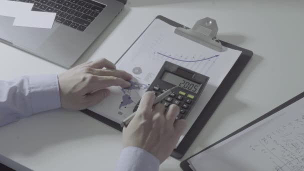 Üzletember kéz dolgozik pénzügyekkel kapcsolatos költségek és számológép és laptop mobiltelefon withe íróasztal a modern irodában - Felvétel, videó