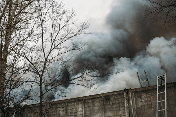 Edificio industrial en llamas y humo negro
 - Foto, Imagen