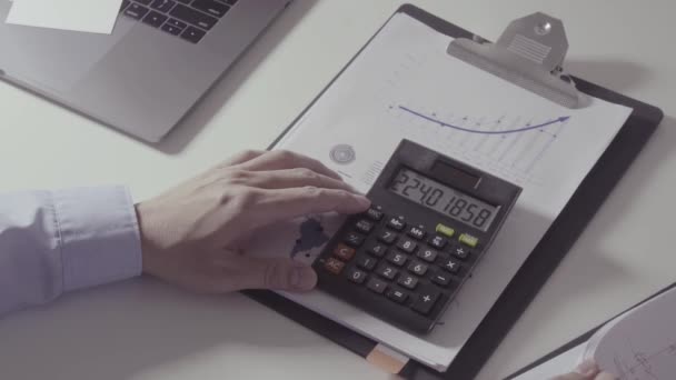 Liikemies käsi työskentelee talouden kustannuksia ja laskin ja kannettava tietokone matkapuhelimella withe työpöydällä modernissa toimistossa
 - Materiaali, video