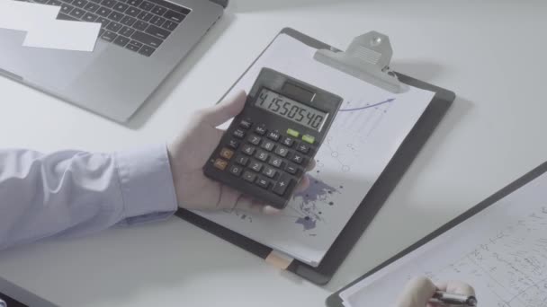 Liikemies käsi työskentelee talouden kustannuksia ja laskin ja kannettava tietokone matkapuhelimella withe työpöydällä modernissa toimistossa
 - Materiaali, video