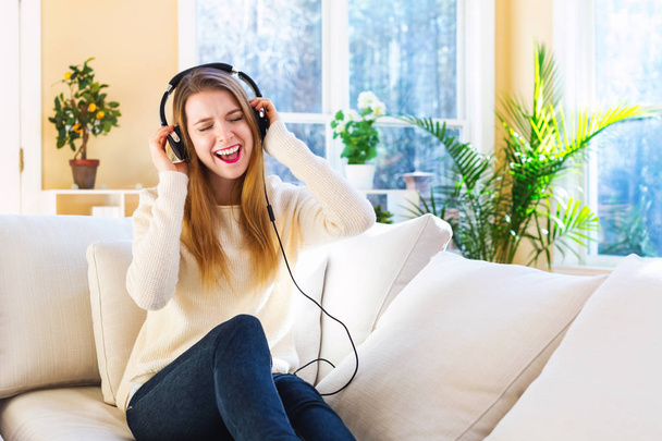 Happy young woman listening to music on headphones - Photo, image