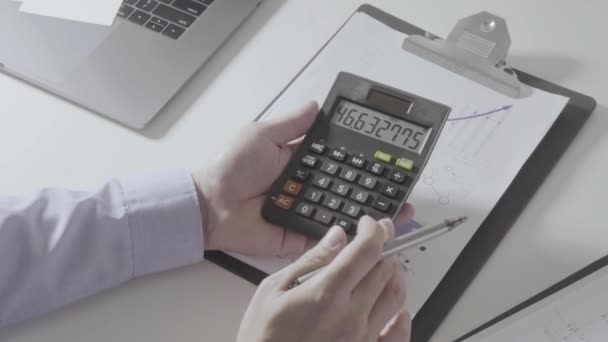 businessman hand working with finances about cost and calculator and laptop with mobile phone on withe desk in modern office - Footage, Video