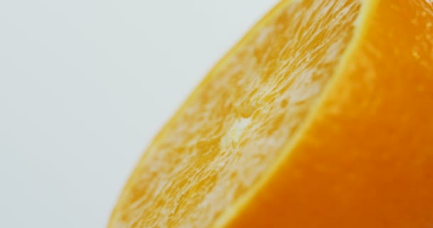 Macro shooting of the half of the orange rolling on the white wall background. Close up - Materiał filmowy, wideo