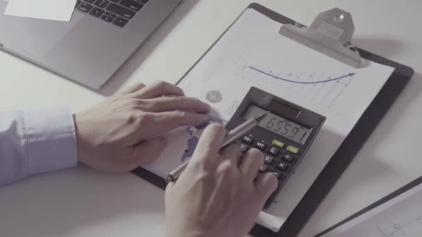 Podnikatel ruční práce s financemi o náklady a kalkulačka a notebook s mobilním telefonem na stole v moderní kanceláři - Záběry, video