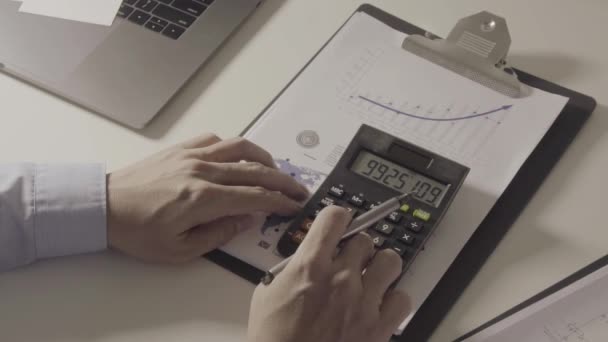 Podnikatel ruční práce s financemi o náklady a kalkulačka a notebook s mobilním telefonem na stole v moderní kanceláři - Záběry, video
