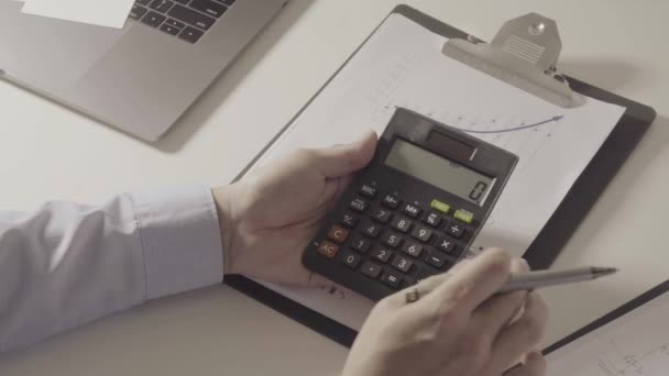 businessman hand working with finances about cost and calculator and laptop with mobile phone on withe desk in modern office - Footage, Video