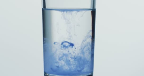 Крупным планом голубые капли краски падают в стакан с водой. Макро
 - Кадры, видео
