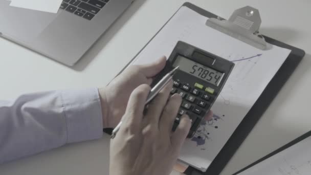 Бизнесмен ручной работы с финансами о стоимости и калькулятор и ноутбук с мобильного телефона на столе withe в современном офисе
 - Кадры, видео