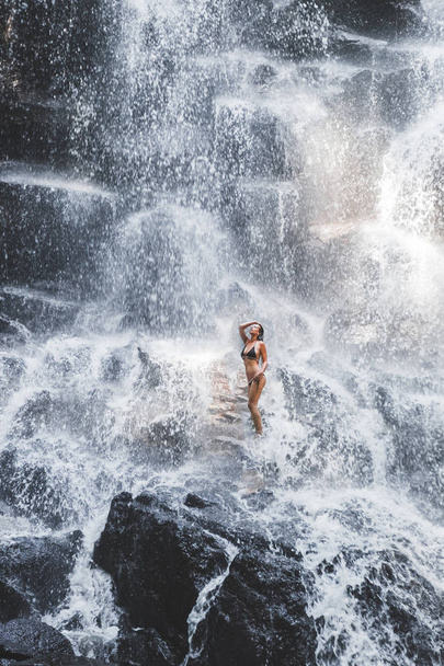 Woman under stream of big waterfall - Photo, Image