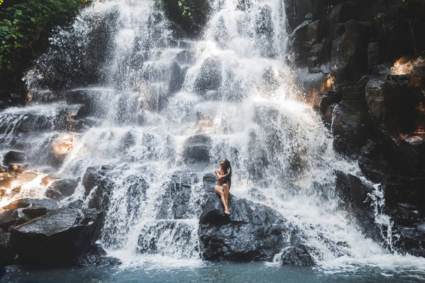 Woman under stream of big waterfall - 写真・画像