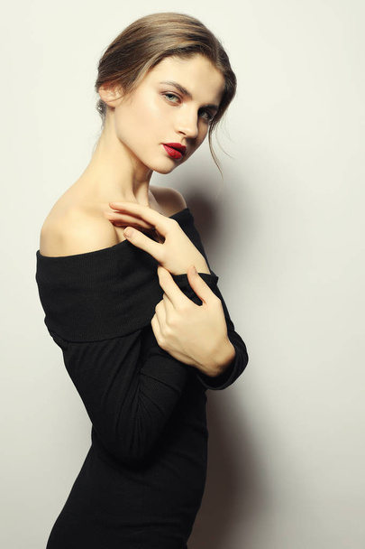 Blond woman in black dress posing with crossed arms and looking  - Foto, afbeelding