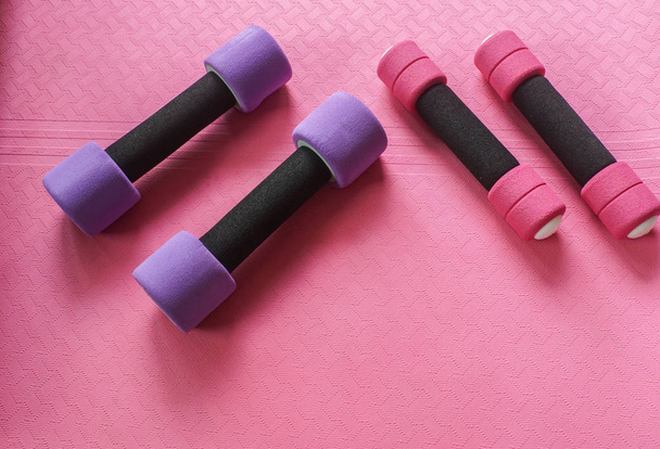 petit haltère rose et grand violet sur tapis de yoga pour les femmes exercice
 - Photo, image
