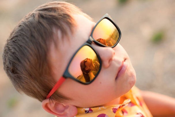 cute little boy with sunglasses that reflect beautiful small girl in summer evening - Fotó, kép