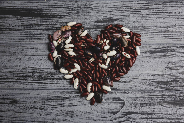 Серце з різнокольорових бобів на дерев'яному столі
 - Фото, зображення
