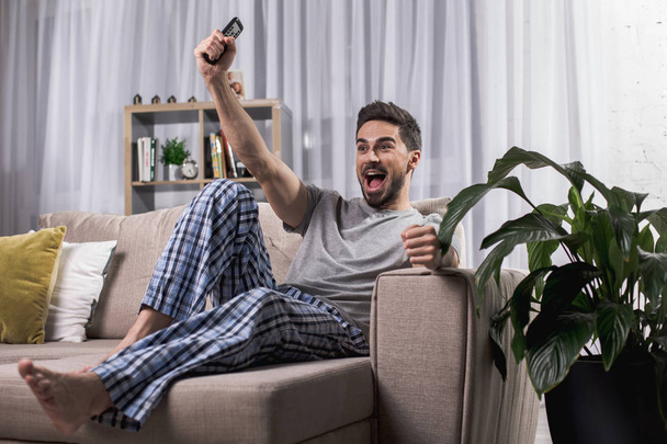 Cheerful guy watching television at home - Zdjęcie, obraz