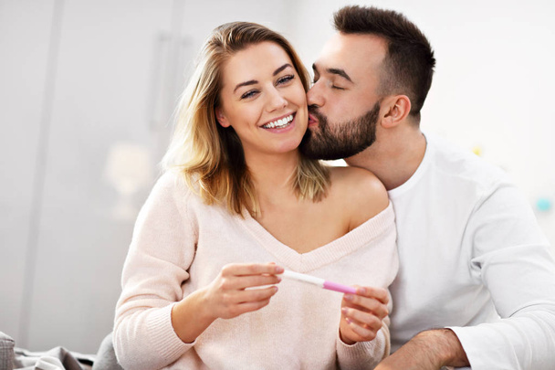 Happy couple with pregnancy test in bedroom - Foto, afbeelding