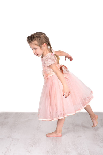 The little girl in a pink ball dress barefoot  does exercise "sw - Foto, Bild
