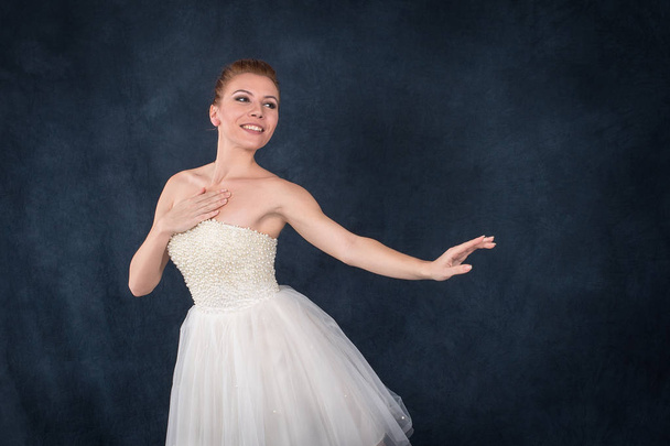 die Ballerina in Spitze und weißem Kleid tanzt auf dunklem Rücken - Foto, Bild
