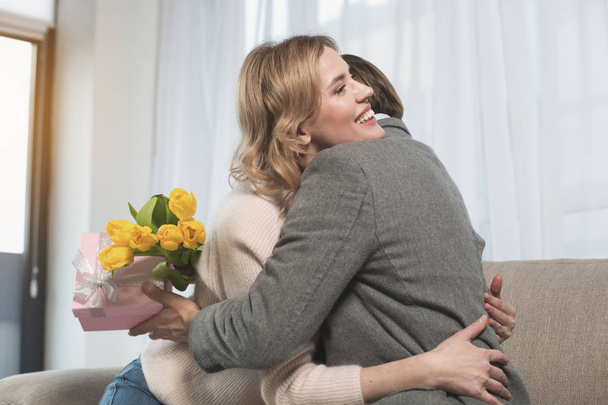 Beaming female embracing husband with presents - Photo, Image