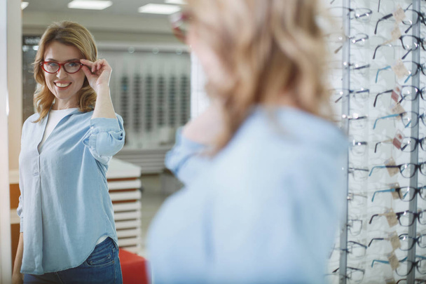 Happy woman admiring reflection in optician shop - Foto, immagini
