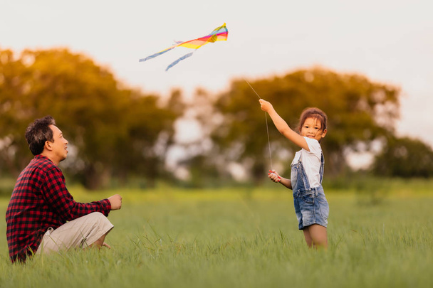 Asian child girl and father with a kite running and happy on mea - Photo, Image