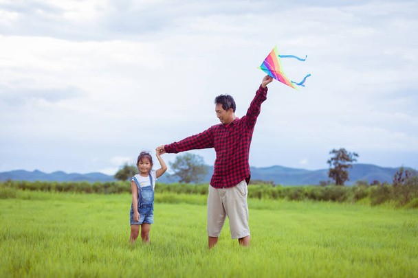 Asian child girl and father with a kite running and happy on mea - Фото, зображення