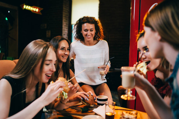 Група молодих дівчат обідали в ресторані фаст-фуду їдять ремісничі гамбургери
 - Фото, зображення