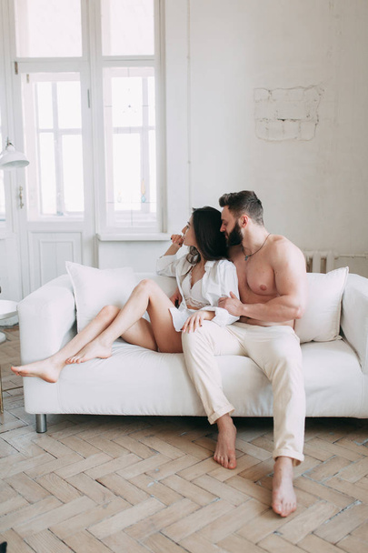 Young happy couple at home, cuddling, and kissing are. Beautiful Sunny morning with your loved ones in pajamas mad and laugh. - Foto, Imagen