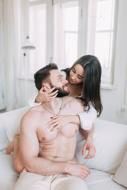 Young happy couple at home, cuddling, and kissing are. Beautiful Sunny morning with your loved ones in pajamas mad and laugh. - Fotoğraf, Görsel