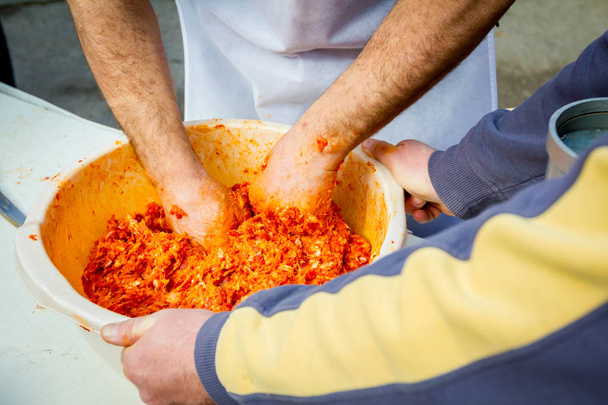 Ihmiset sekoittavat jauhelihaa käsintehtyihin makkaroihin ulkona keittiössä
 - Valokuva, kuva