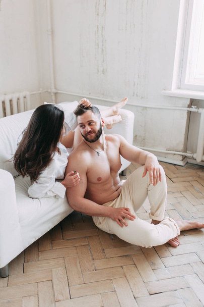 Young happy couple at home, cuddling, and kissing are. Beautiful Sunny morning with your loved ones in pajamas mad and laugh. - Фото, изображение