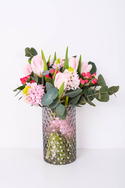 Boquet of pink flowers in vase by white wall - Foto, afbeelding