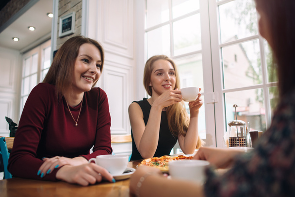 Amis féminins buvant du café ayant une conversation agréable dans un restaurant romantique confortable
 - Photo, image