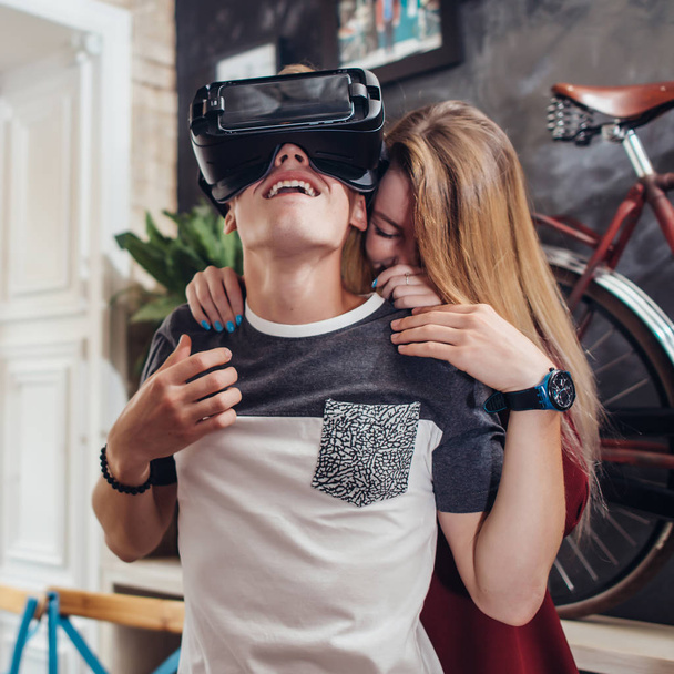 Boyfriend and girlfriend testing new vr 3d vision headset spending time together having fun laughing at home - Photo, Image
