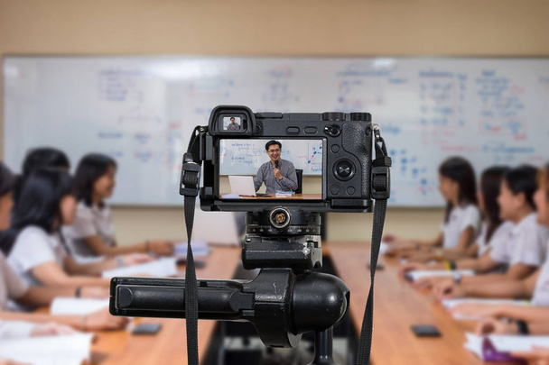 Цифровая камера на штативе, записывающая видео азиатского учителя в классе, фотоаппарат для фотографа и концепция Technology Live Streaming, концепция университетского образования
 - Фото, изображение