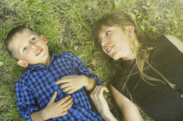 roztomilý chlapeček, malé, málo, synu a krásná matka, Žena, ležící na zelené trávě na slunné jarní příroda  - Fotografie, Obrázek