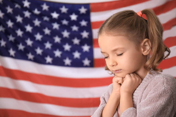 Cute little girl praying for America and flag on background - Fotoğraf, Görsel